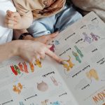 A comforting moment of a mother reading a colorful picture book with her child.